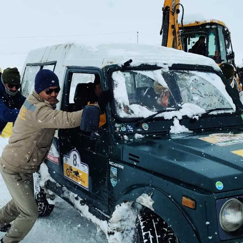 Policemen helping move a stuck vehicle outside atal tunnel in snow.